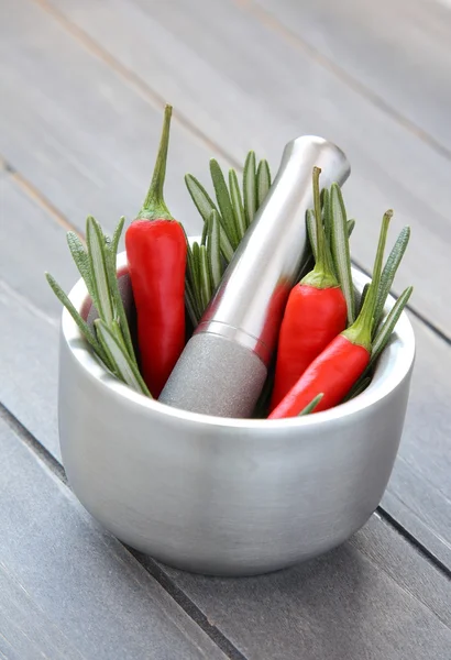 Verse rozemarijn kruid en rode paprika in metalen mortier met stamper — Stockfoto