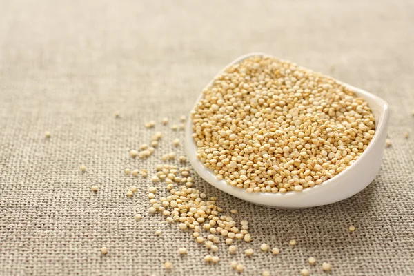 Grain de quinoa dans un bol en céramique blanche sur fond de sac — Photo