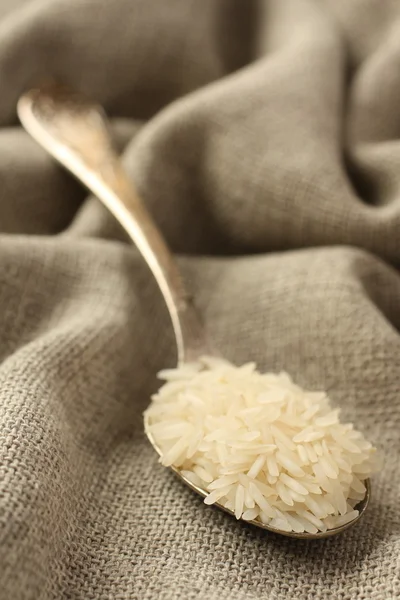 Polished long rice grains in metal spoon — Stock Photo, Image