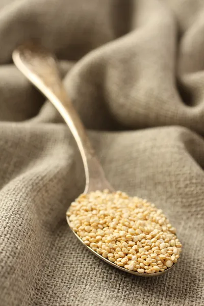 Quinoa graan in metalen lepel op rouwgewaad achtergrond — Stockfoto