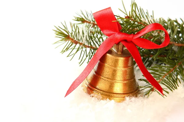 Zlatý zvon s červenou stuhu a větve vánočního stromu — Stock fotografie