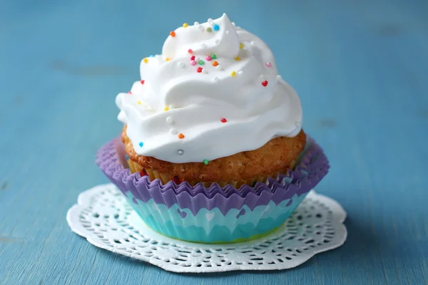 Cupcake with white cream icing and candy sprinkles — Stock Photo, Image