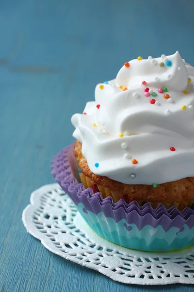 Cupcake with white cream icing and candy sprinkles — Stock Photo, Image
