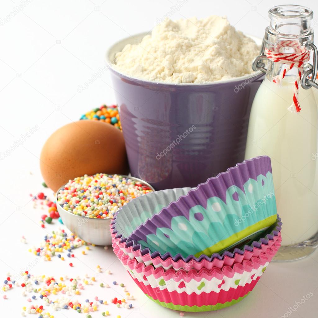 Cupcake cases and ingredients over white with copyspace