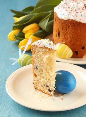 Paskalya ekmek ile renkli yumurta ve mavi ahşap zemin üzerine Sarı laleler