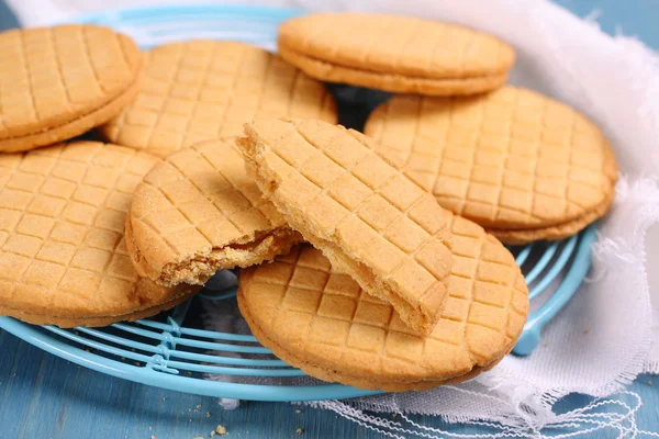 Sandwich biscuits with syrup filling on blue wooden background — Stock Photo, Image