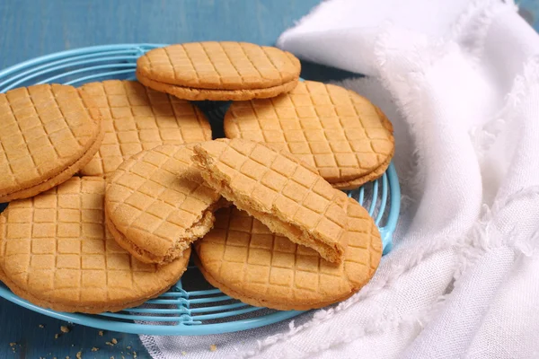 Sandwich biscuits with syrup filling on blue wooden background — Stock Photo, Image