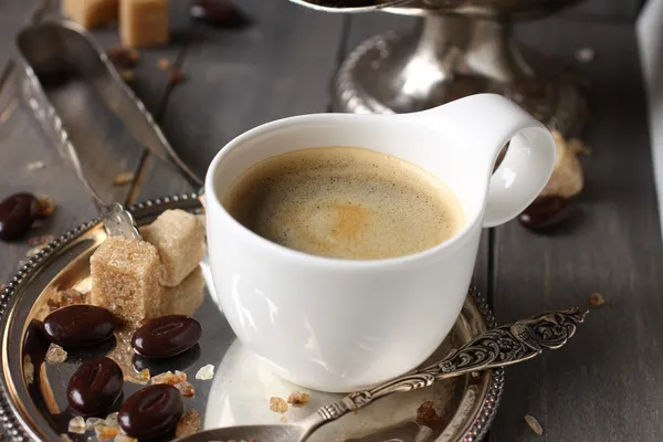 Xícara de café expresso, cubos de açúcar e doces de chocolate em fundo de madeira rústica — Fotografia de Stock
