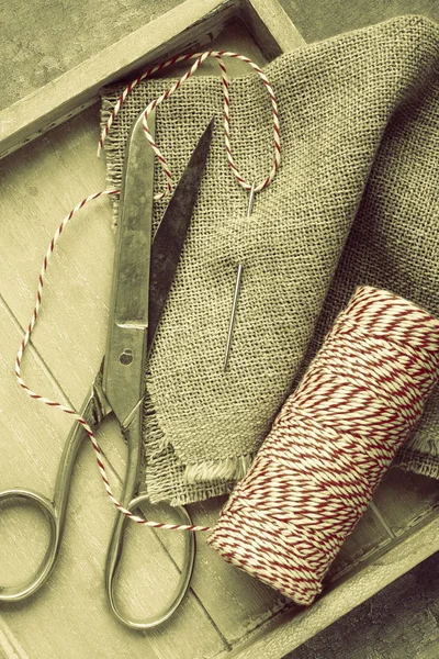 Tijeras, carrete de hilo, aguja y saco en bandeja de madera — Foto de Stock