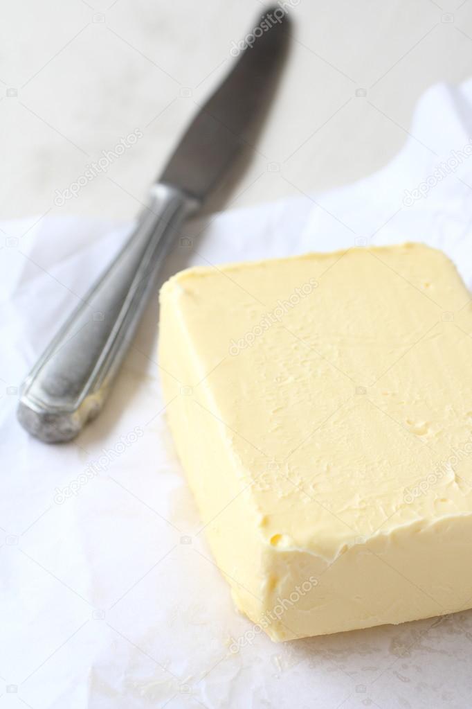 Piece of butter in paper with khife