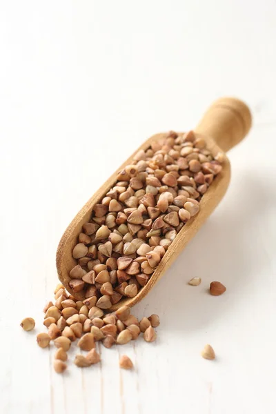 Wooden scoop with buckwheat grain on white background — Stock Photo, Image