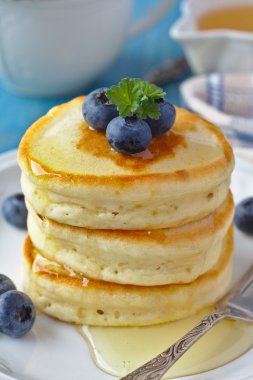 Bal ve bir kahvaltı masası üzerinde yaban mersini ile viski krep yığını