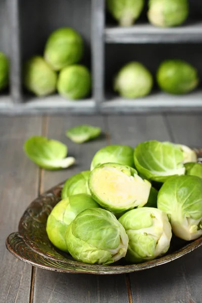 Frische rohe Rosenkohl-Sprossen in Metallplatte auf Holzgrund — Stockfoto