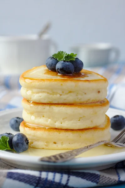 A stack of scotch pancakes with with honey and blueberries on a breakfast table — Stock Photo, Image