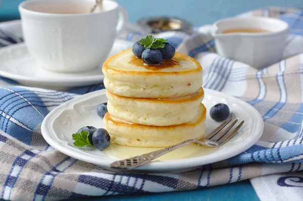 Une pile de crêpes au scotch avec du miel et des bleuets sur une table de petit déjeuner — Photo