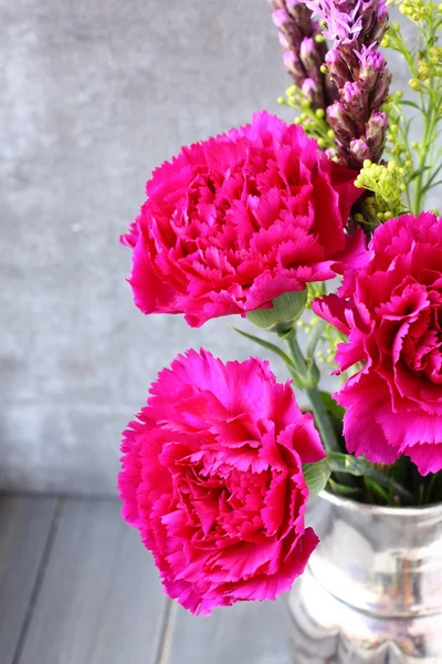 Ramo de flores de claveles rosados en jarrón de metal sobre fondo rústico de madera —  Fotos de Stock