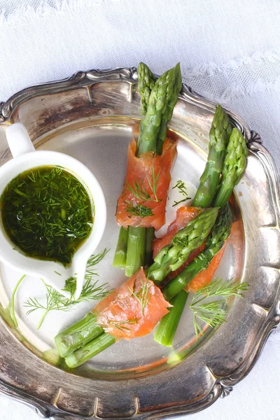 Asperges enveloppées dans du saumon fumé avec sauce à l'aneth sur une assiette en métal — Photo