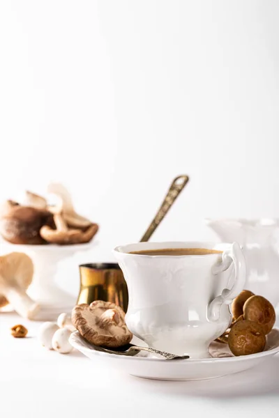 Trendy mushroom coffee in white porcelain vintage cup over white background. New Superfood Trend. Copy space, selective focus.