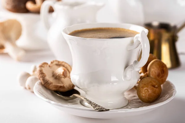 White porcelain vintage cup with mushroom coffee on white background. New Superfood Trend, selective focus.