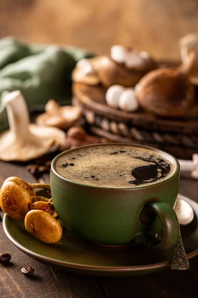 Mushroom coffee in green cup on wooden background. New Superfood trendy healthy concept, selective focus.