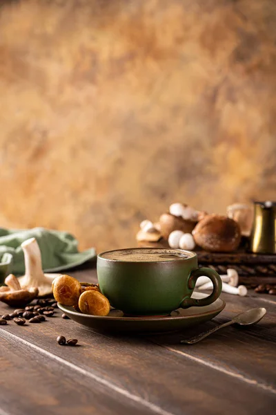 Trendy superfood mushroom coffee in green cup on wooden background. Healthy concept with copy space, selective focus.