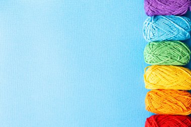 Gökkuşağı renkli iplik ile örgü arkaplan mavi üzerinde, üst görünüm, düz kopya alanı ile yatar