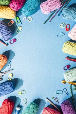 Örgü arka planında çeşitli renkli iplikler ve örgü aksesuarları mavi, üst görünümde, düz yerde fotokopi alanı var. Retro biçimi