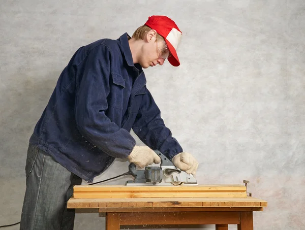 The worker operates electric planer — Stock Photo, Image