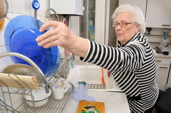 Senior woman puts plate — Stock Photo, Image