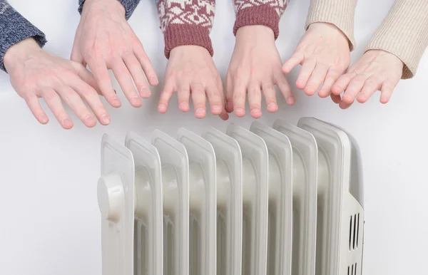 Família aquecendo as mãos sobre aquecedor elétrico — Fotografia de Stock