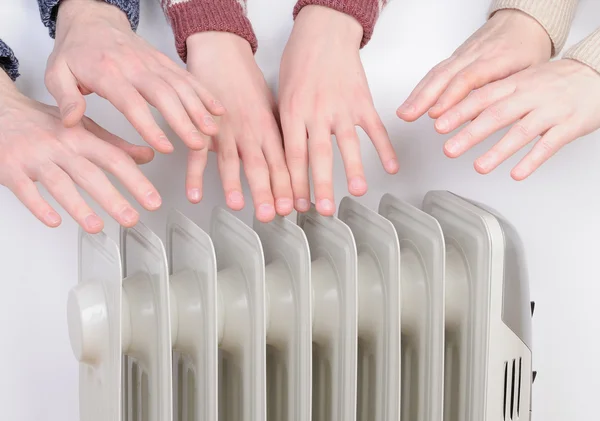 Familia calentando manos sobre calentador eléctrico — Foto de Stock