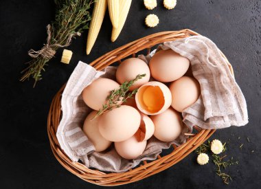Household. Farm products. Raw eggs in a basket. Corn, thyme on a black table. Farm products. Background image, copy space, flatlay, top view