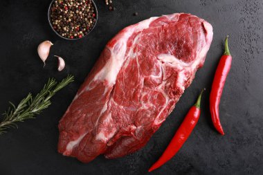 Raw meat. Steak beef  with spices, rosemary, red chili pepper, garlic on a black table. Background image, copy space, flatlay, top view