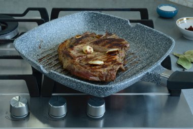 Kemiğin üzerinde bir parça domuz kızartma tavasında kızartılmış. Ev mutfağında kızartma tavasında et pişirmek.