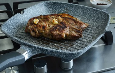 Sarımsaklı et parçası, kıvrımlı tavada kızartılmış. Kızarmış et, iyi pişmiş biftek.