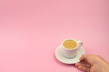 Pembe Arkaplanda Kadın El Tutuşu Kahve Fincanı, Üst Manzara, Kopya Alanı. Bir fincan kahve.