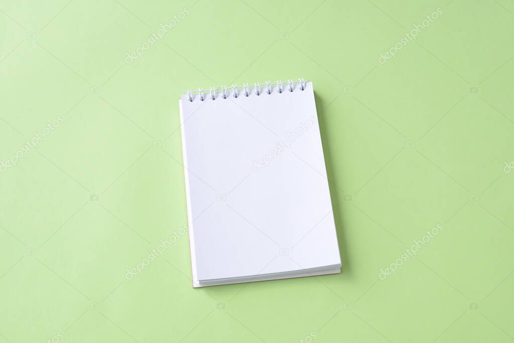 Blank spiral notepad notebook. Open spiral notepad on a green background. Flat lay. Space for yor text