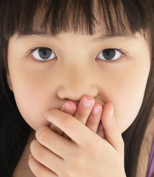 Scared little girl covering mouth with hand