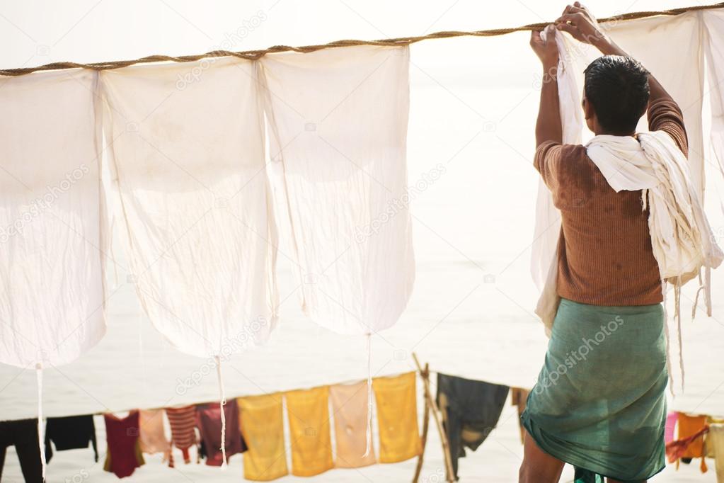 Indian old man hang the wash on a clothesline