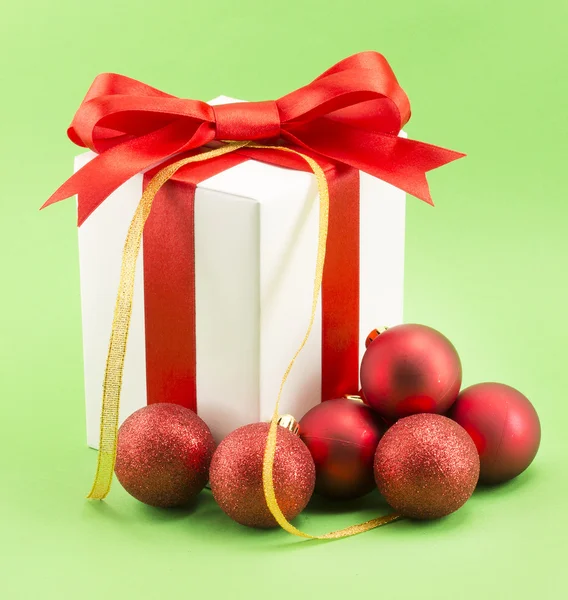 Caixa de presente branco com fita vermelha arco e bolas de Natal — Fotografia de Stock