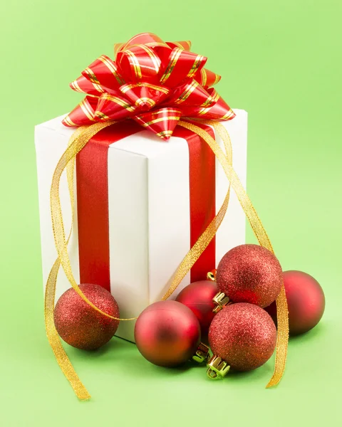 Kırmızı kurdeleli beyaz hediye kutusu ve Noel topları. — Stok fotoğraf
