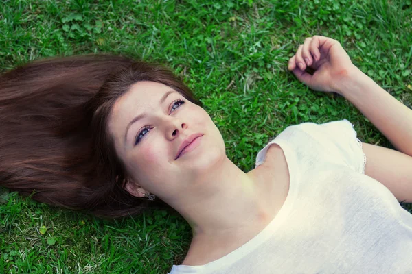 Krásná mladá žena ležící na trávě — Stock fotografie