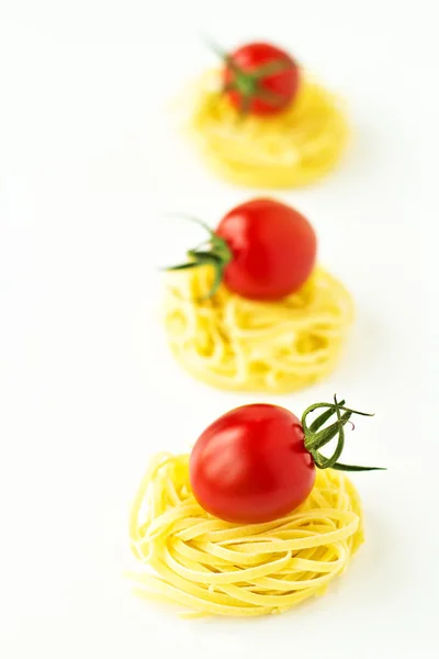 Nidos de pasta con tomates cherry y albahaca sobre fondo blanco — Foto de Stock