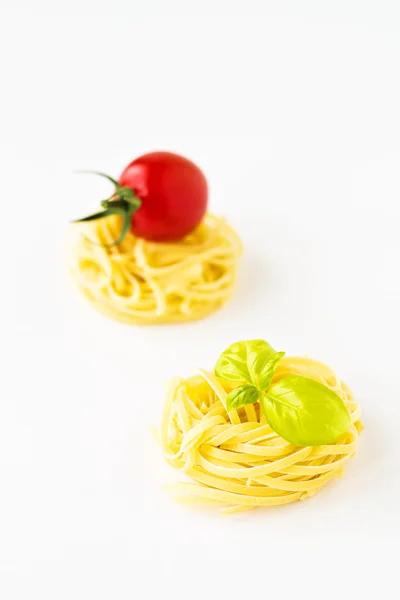 Gniazda makaron z pomidorami i bazylia na białym tle — Zdjęcie stockowe