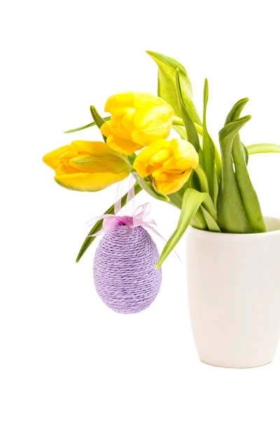 Жовті тюльпани в білій вазі з пасхальним яйцем на білому — стокове фото