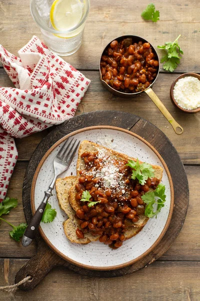 Bakade bönor med bacon på rostat bröd — Stockfoto