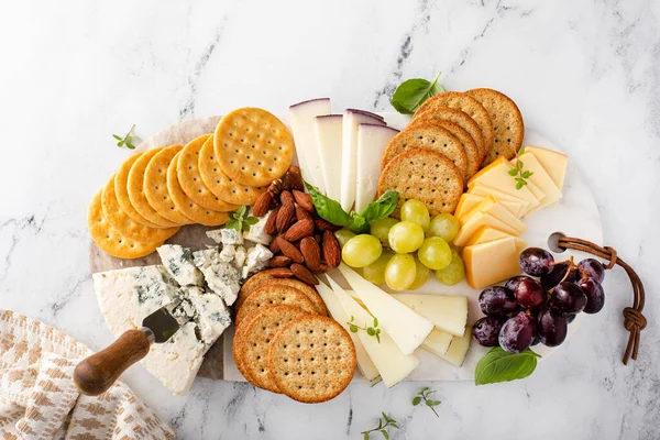 Cheese board with crackers, nuts and grapes — Stock Photo, Image