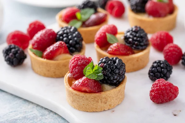 Fresh berries tartlets with custard filling and mint — Stock Photo, Image