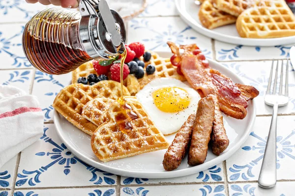 早餐桌上有华夫饼。煎蛋、咸肉和香肠 — 图库照片