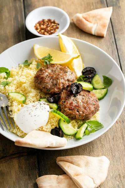 Galettes de dinde aux herbes servies avec couscous et salade fraîche — Photo